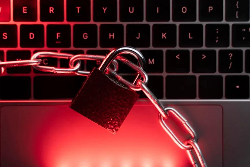 Imagem ilustrando bloqueio criativo, com um cadeado e corrente sobre um teclado de computador iluminado em tons vermelhos