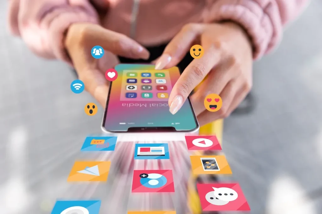 Pessoa interagindo com um smartphone, exibindo ícones coloridos de aplicativos de redes sociais e reações emocionais.