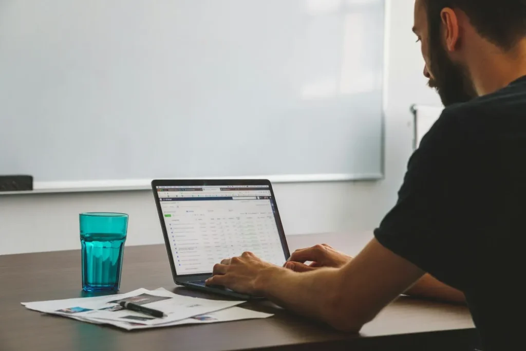 Homem usando notebook com gerenciador de anúncios aberto em ambiente de trabalho.