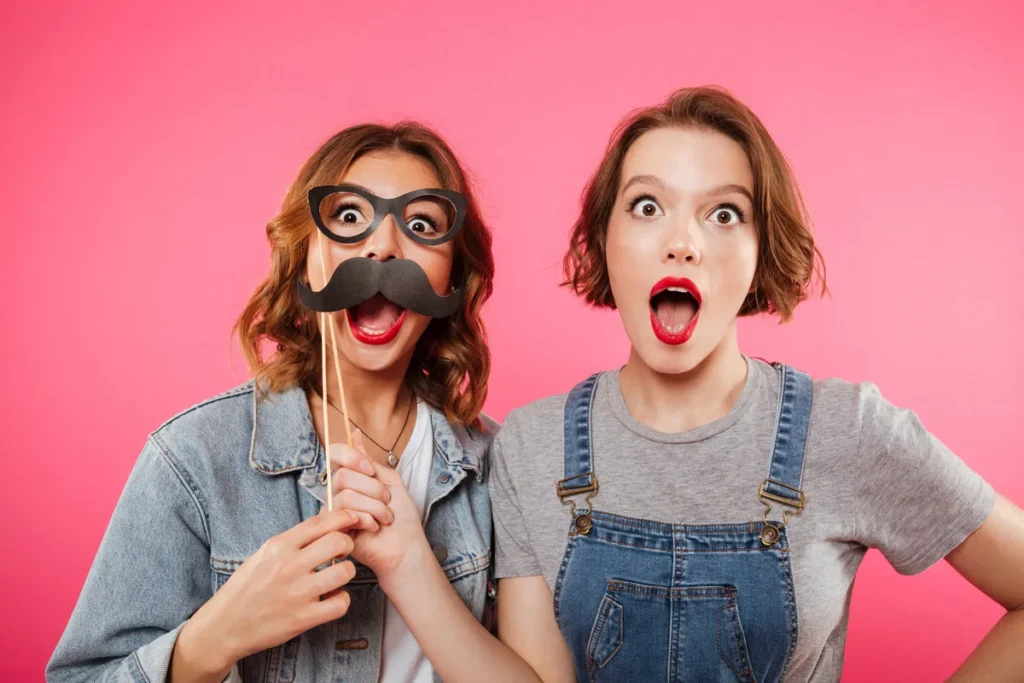 Duas amigas fazendo careta com acessórios de fantasia