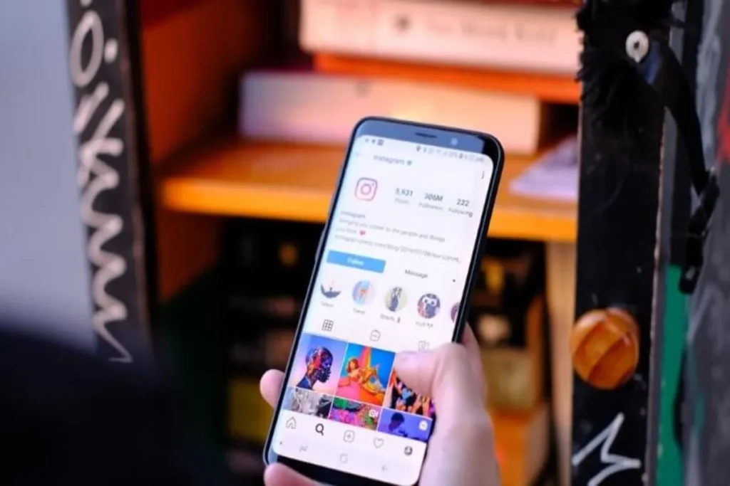 Mão segurando um celular com o aplicativo do Instagram aberto, usando a palavra-chave "Gerenciador de Anúncios Instagram".
