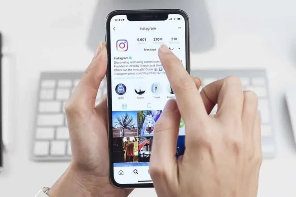 Mãos usando um celular com o aplicativo do Instagram aberto e a palavra-chave "Gerenciador de Anúncios Instagram".