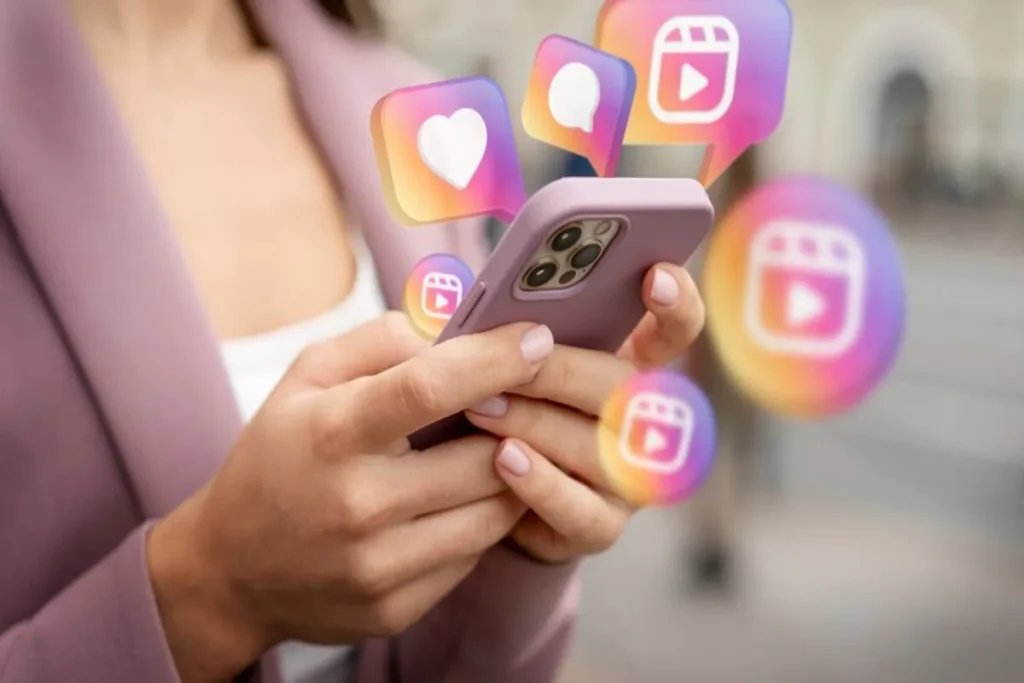 Mãos segurando um celular com ícones flutuantes do Instagram (curtir, comentar, Reels) com a palavra-chave "Gerenciador de Anúncios Instagram".