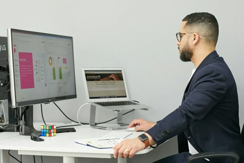 Homem de negócios rastreando resultados de marketing com a palavra-chave UTM em dois monitores.