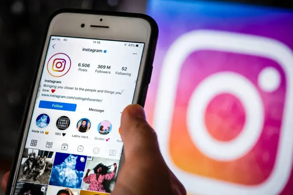 Uma mão segurando um celular com o aplicativo do Instagram aberto no perfil, com o logo do aplicativo ao fundo. A imagem representa como um heatmap pode ser usado para analisar o engajamento e a popularidade de um perfil na rede social.