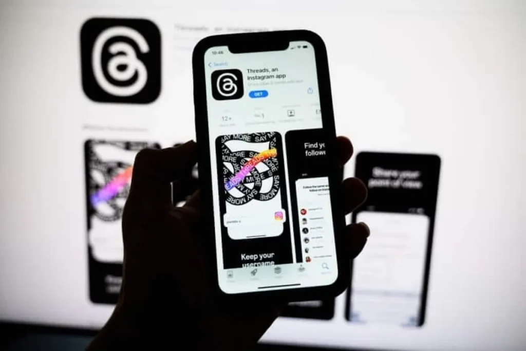 Pessoa segurando smartphone com a página de download do aplicativo Threads, do Instagram, na App Store.