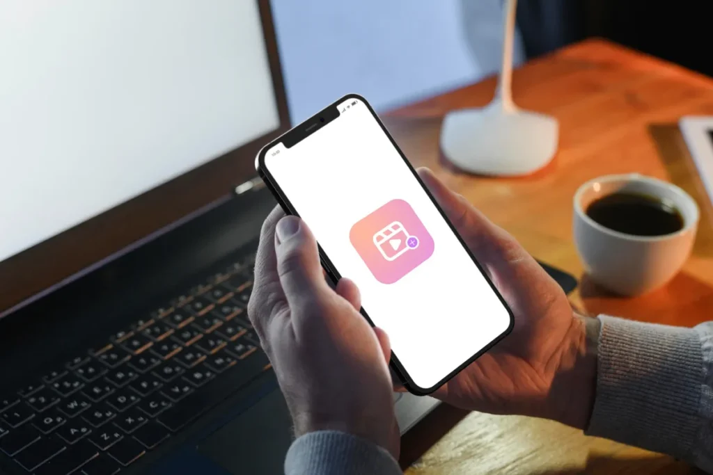 Pessoa segurando um celular com o ícone do Instagram Reels na tela, representando a criação de vídeos com música para Reels.