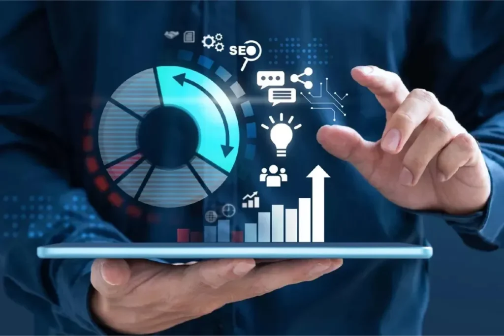 Pessoa segurando um tablet com ícones e gráficos de marketing digital, como um gráfico de pizza azul, um gráfico de barras e ícones de SEO e compartilhamento. Representação de análise de tráfego pago.